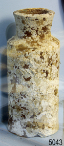 White clay bottle with wide mouth. Encrustations are on the surface.
