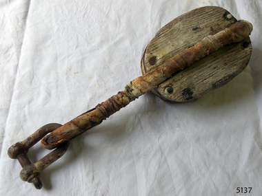 Oval wooden block with metal arm connected to a  'D' bolt