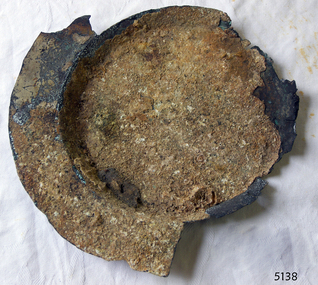 Metal plate with a wide rem and deep bowl. Encrusted, corroded, parts missing