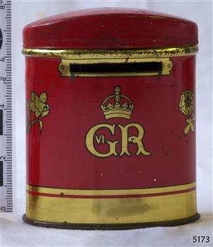 Tin cylinder with domed lid, Red with gold inscriptions and decoration. Top edge of base has a slit.