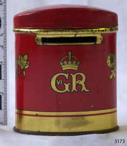 Tin cylinder with domed lid, Red with gold inscriptions and decoration. Top edge of base has a slit.