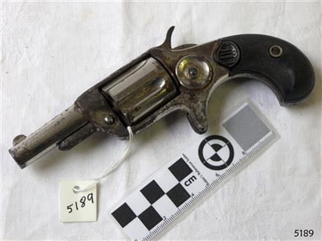 Pistol on bench, action on right, metal grip and barrel