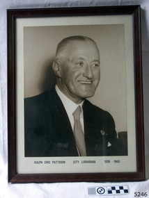 Sepia framed portrait, male in suit and tie, facing towards his left, smiling