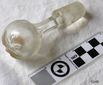 Glass bottle stopper's top has floral motif, neck is six-sided, stopper base is textured glass