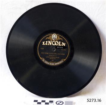 A flat black disc with spiralling grooves and a black and gold label around the central hole