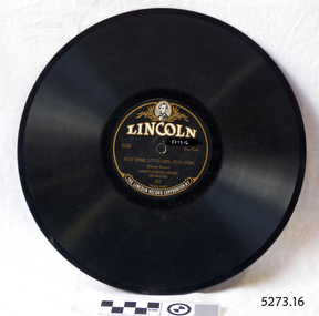 A flat black disc with spiralling grooves and a black and gold label around the central hole