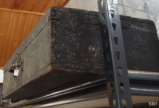 the join of the opening lid is on the right, hook attached but no latch, rough surface of the box is evident