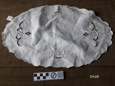 Oval shaped cotton doily with decorative edge and cut out embroidery