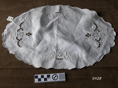 Oval shaped cotton doily with decorative edge and cut out embroidery