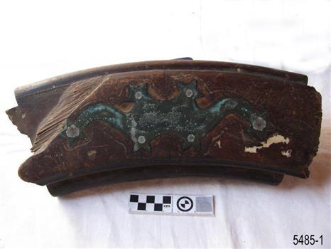 Helm is arc of wood with decorative metal attachment