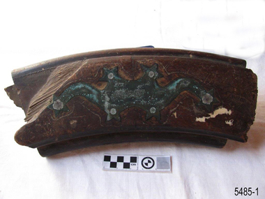 Helm is arc of wood with decorative metal attachment