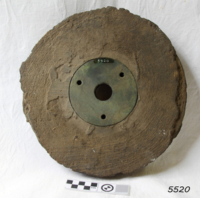 Wooden pully sheeve, petrified,  with metal disc in centre