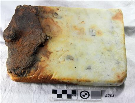 Rectangular block of cream marble with a round knob at one end and brown discolouration