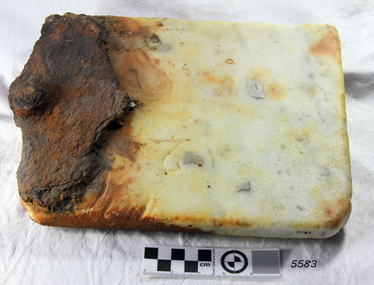 Rectangular block of cream marble with a round knob at one end and brown discolouration