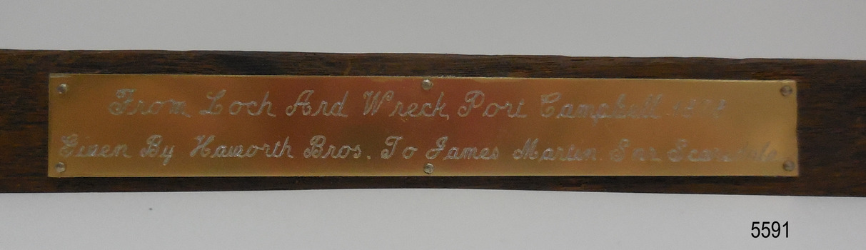 Gold coloured plaque with inscription in script wriging