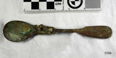 Spoon in golden colour covered with black and green marks and sea crustaceans