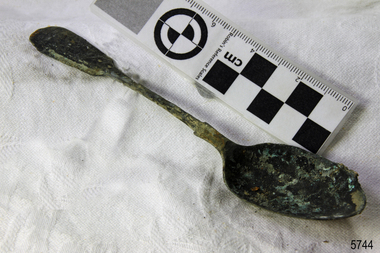 A large spoon golden in colour covered in black marks
