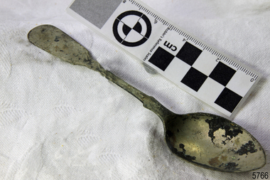 A large spoon golden in colour covered in black marks