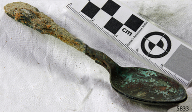 Spoons stuck together golden in colour covered in black and green marks and sea crustaceans