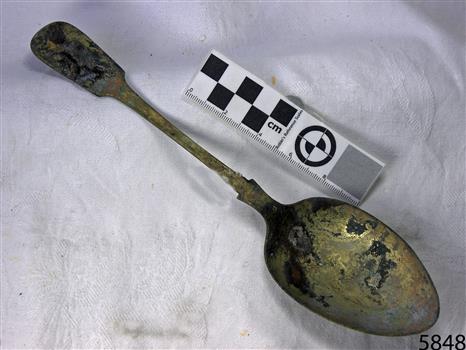 Spoon in golden colour covered with black and green marks 