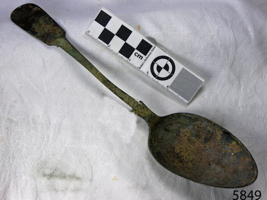 Spoon in golden colour covered with black and green marks