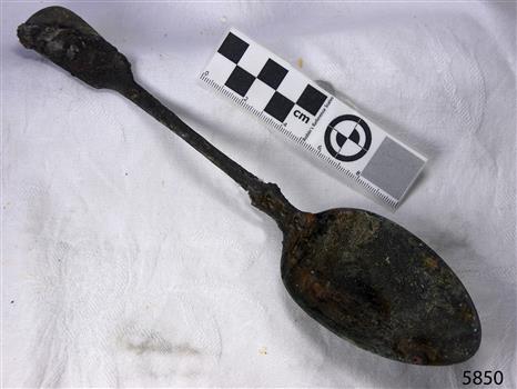 Spoon in golden colour covered with black and green marks 