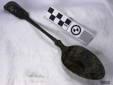 Spoon in golden colour covered with black and green marks 