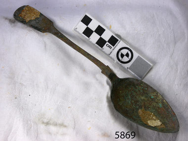 Spoon in golden colour covered with black and green marks and sea crustaceans