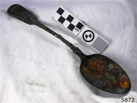 Spoon in golden colour covered with black and green marks and sea crustaceans