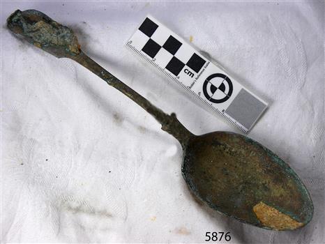 Spoon in golden colour covered with black and green marks and sea crustaceans