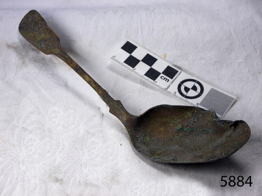 Spoon in golden colour covered with black and green marks and sea crustaceans