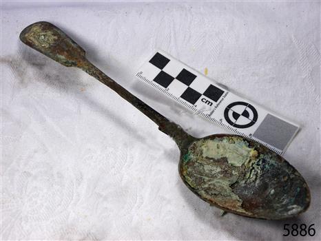 Spoon in golden colour covered with black and green marks and sea crustaceans