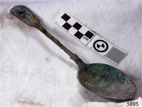 Spoon in golden colour covered with black and green marks and sea crustaceans