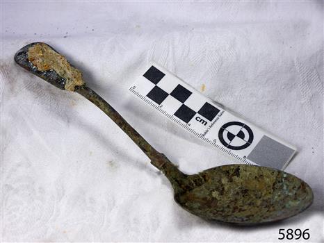 Metal spoon is bent and the surface is damaged by sea water and encrustations