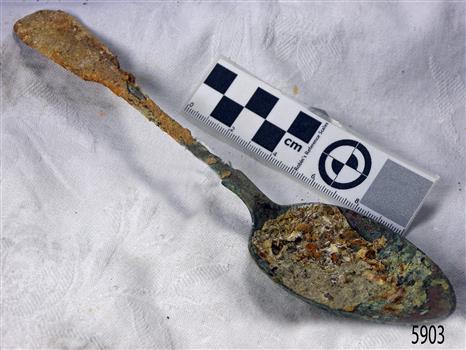Metal spoon is degrading and has a covering of encrustations