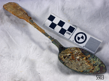 Metal spoon is degrading and has a covering of encrustations