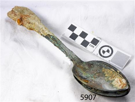 Spoons stuck together golden in colour covered in black and green marks and sea crustaceans