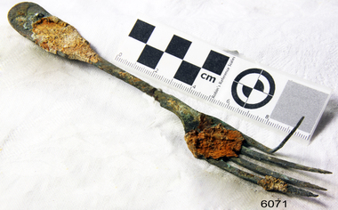 Fork in golden colour covered with black and green marks and sea crustaceans