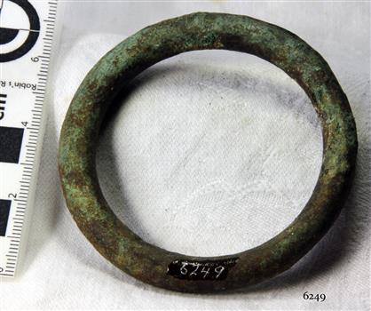 Metal tubular ring with verdigris surface and uneven shape
