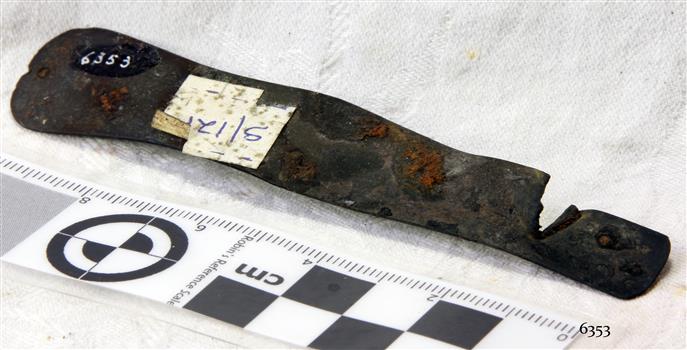 Metal pocket knife section, drilled holes, corroded, sticker attached