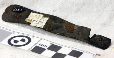 Metal pocket knife section, drilled holes, corroded, sticker attached