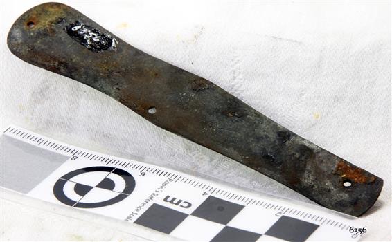 Rounded metal bar with drilled holes and encrustations