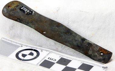 Rounded metal bar with drilled holes and encrustations
