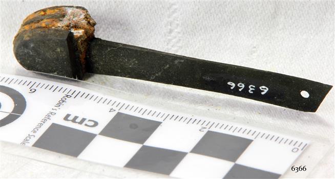 Part of metal end section with blade, corroded