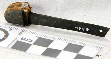 Part of metal end section with blade, corroded