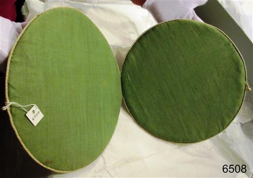 Two green fabric covered circles are joined at the edges for a short distance, creating a book-like case