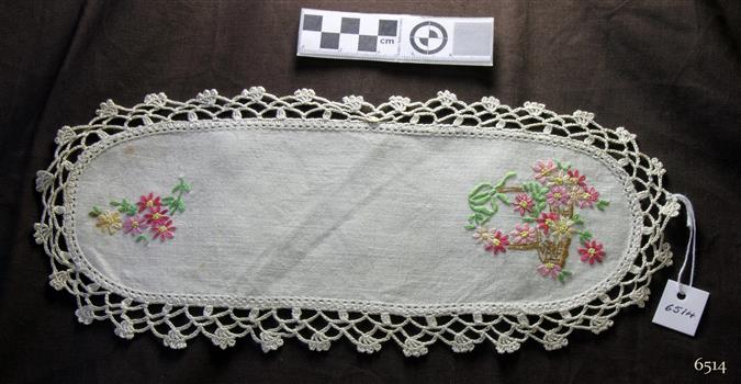 White cotton, oval shaped doily with floral pattern and crocheted edging