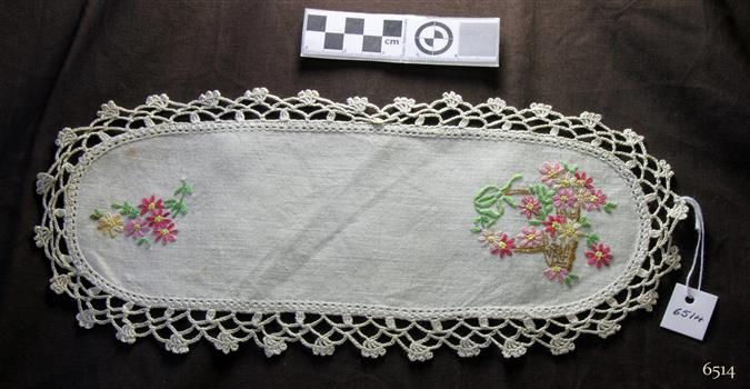 White cotton, oval shaped doily with floral pattern and crocheted edging
