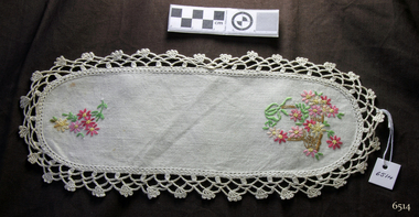 White cotton, oval shaped doily with floral pattern and crocheted edging