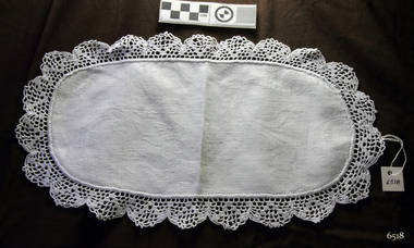 Oval white doily with crocheted edging